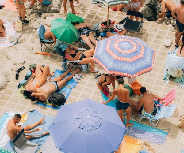 pexels-photo-18088328-18088328 Colorful beach umbrellas and sunbathers at Santa Cesarea Terme, Italy, create a lively summer scene.