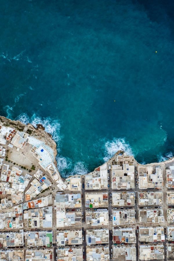 Drone shot of Polignano a Mare showcasing urban coastline against the blue sea.