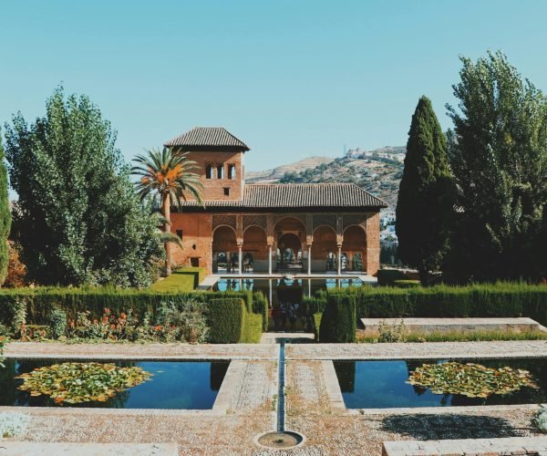 Beautiful view of El Partal in Alhambra, Granada, featuring lush gardens and reflective pools.