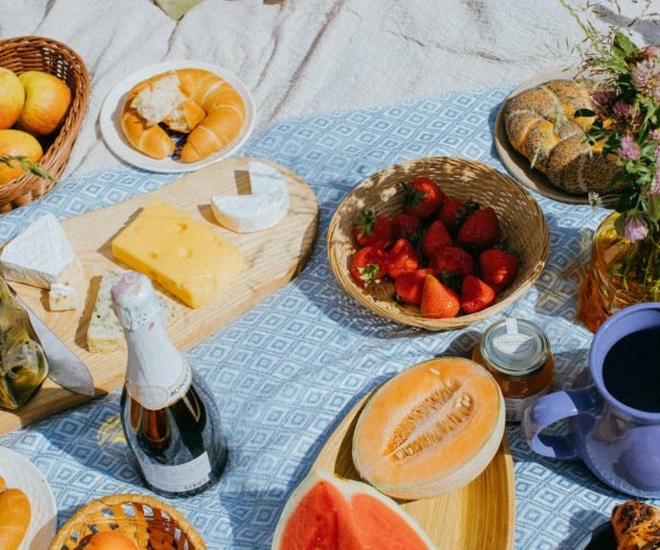 pexels-photo-8530483-8530483 A cozy summer picnic featuring fresh fruits, cheese, and wine on a sunny day.